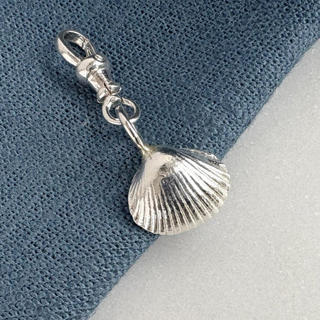 Silver shell charm on a blue and gray background