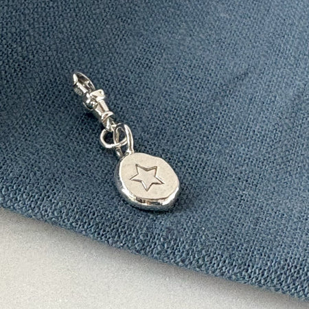 Silver charm with star design on a blue fabric background