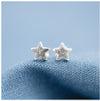 Sterling silver star stud earrings on a blue linen background