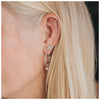 Tiny dot studs or earrings made from  sterling silver in the top of a blonde ladies ear as part of an ear stack with hoops and a star earring