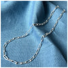 Simple trace chain necklace on a wooden background with a blue linen material on top