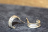 Pair of silver hoop earrings on a dark textured surface