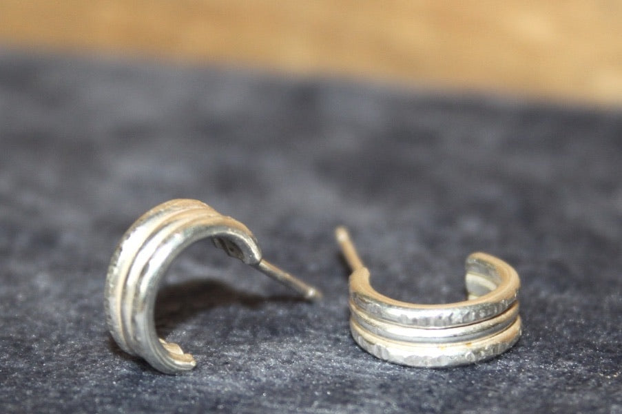 Pair of silver hoop earrings on a dark textured surface