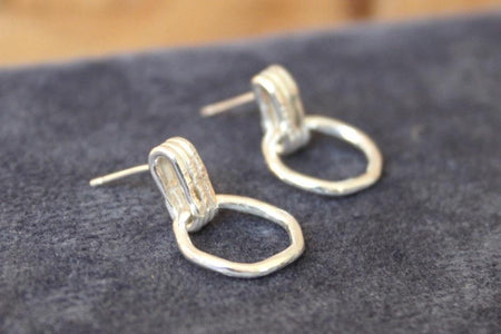 Pair of silver hoop earrings on a dark fabric background