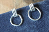 Pair of silver hoop earrings on a dark blue fabric background