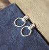 Silver earrings on a blue fabric background