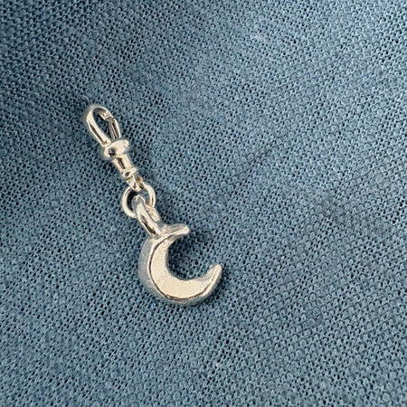 Silver crescent moon charm on a blue textured background