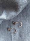Pair of gold hoop earrings on a textured gray fabric background