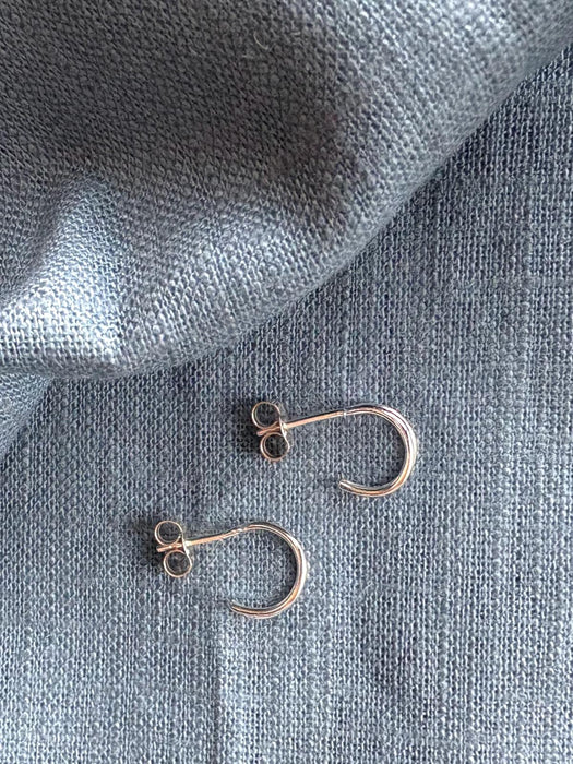 Pair of gold hoop earrings on a textured gray fabric background