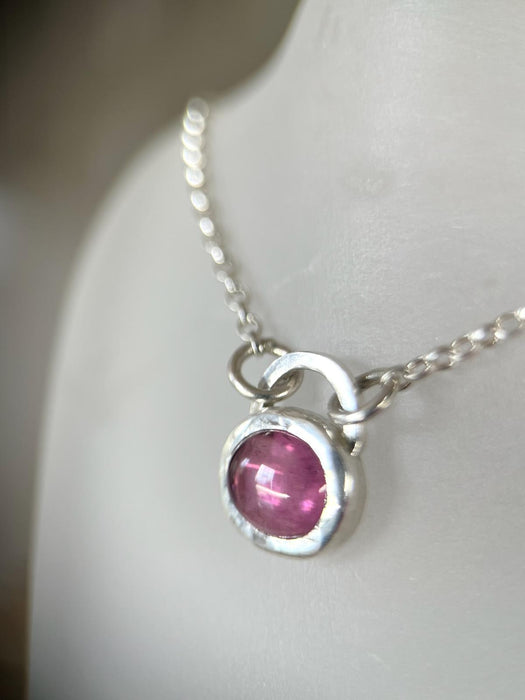 A sterling silver pendant with an oval pink tourmaline stone on an 18'' belcher chain.