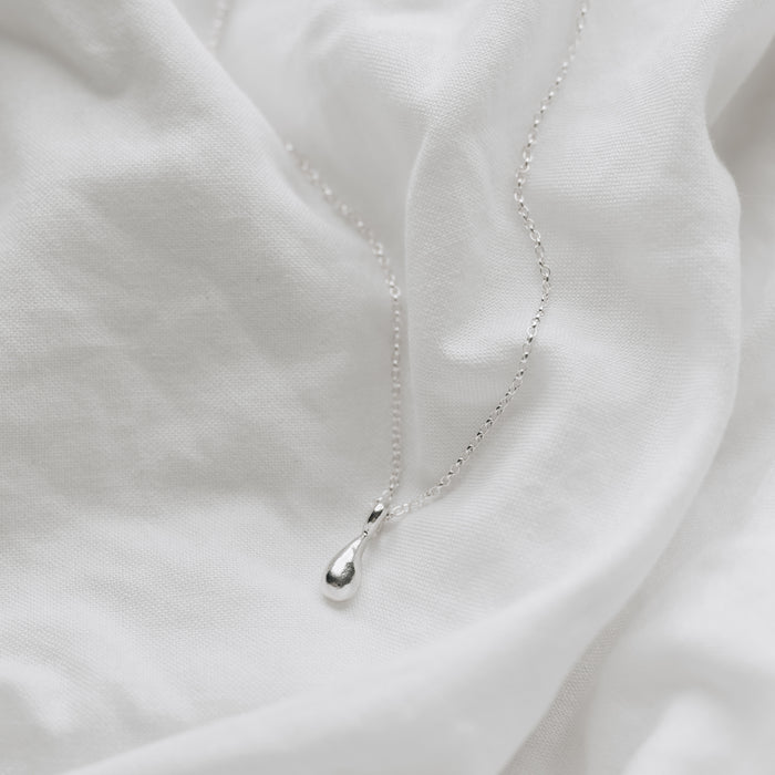 a delicate silver droplet hanging on a belcher chain
