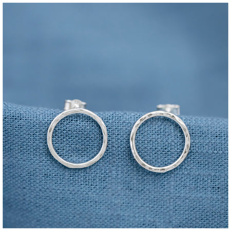silver halo circle earrings on a contrasting blue linen background