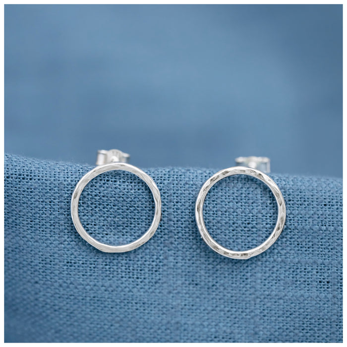silver halo circle earrings on a contrasting blue linen background