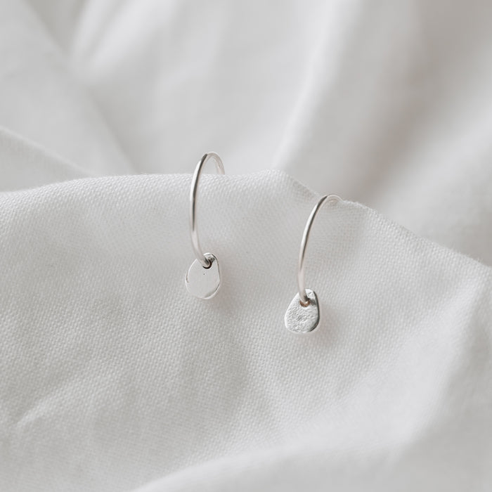 silver hoops with a small pebble on a white linen background