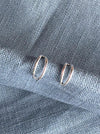Silver hoop earrings on a textured blue fabric background