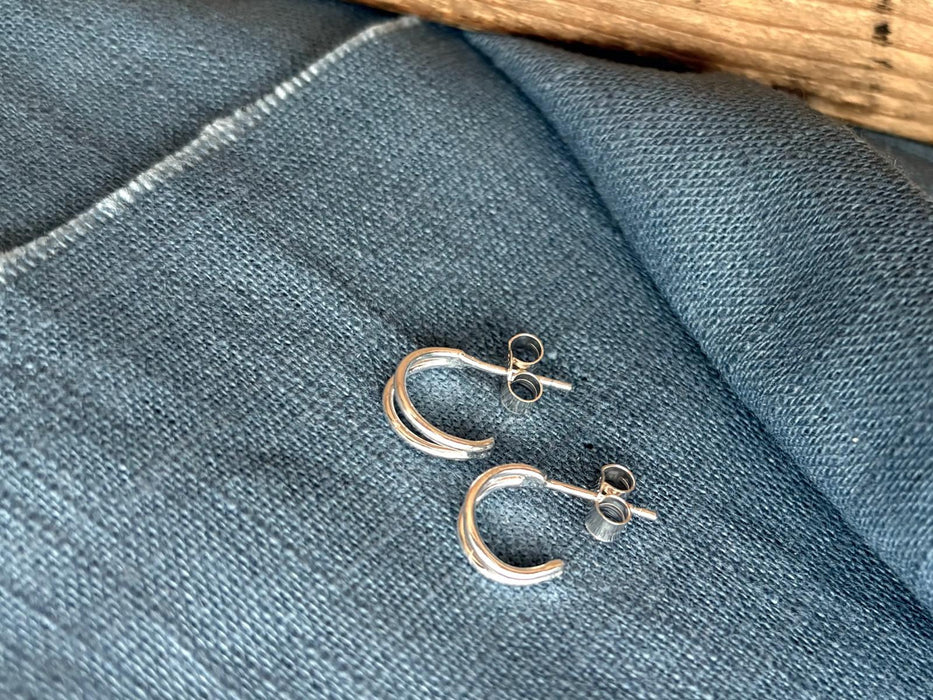 Silver hoop earrings on a blue fabric background