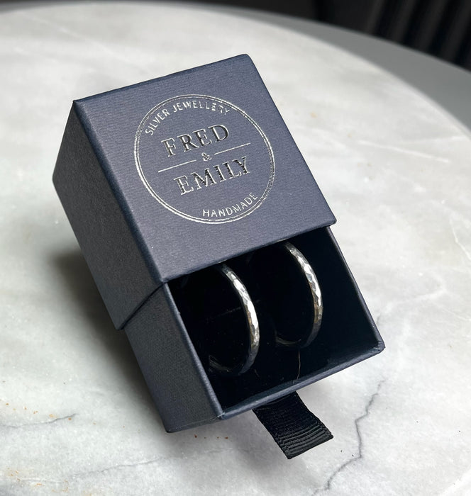 Silver midi medium Hammered Hoop in a Fred & Emily jewellery box on marble background